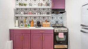 A kitchen with purple cabinets, a gas stove, and a built-in oven. - Brigitte Suite · Adults-Only PS Boutique· Dog Yard (Palm Springs)