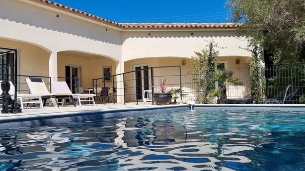 Un  área de piscina con sillones de descanso y una pérgola.