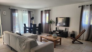 Una sala de estar moderna con sofá, mesa de centro, televisor y zona de comedor.