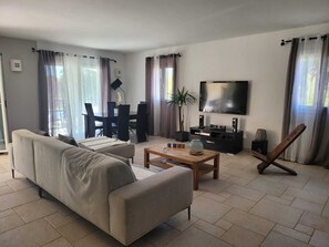 Un soggiorno moderno con un divano, un tavolino, una TV e un'area pranzo.