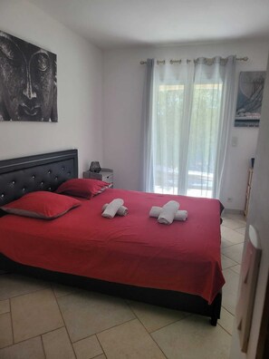 Una camera da letto con un letto, biancheria rossa, un comodino, una lampada e un quadro appeso al muro.