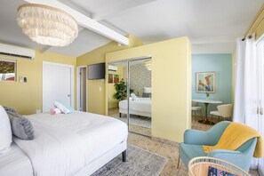 A bedroom with a bed, a chair, a television, and a dining area with chairs and a table. - Audrey Suite · Dog yard + pool, 3 min to downtown (Palm Springs)