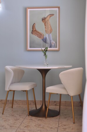 Un comedor con una mesa redonda, dos sillas y un cuadro en la pared.