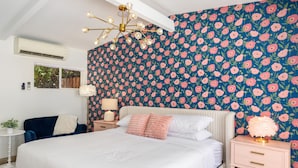 Une chambre à coucher avec un grand lit, une table de chevet, une lampe et un papier peint à motifs floraux.