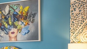 Une chambre à coucher avec une tête de lit à motifs floraux, une lampe de chevet et un tableau mural.
