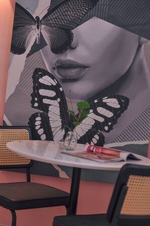 Une table avec un vase rempli de feuilles vertes, un magazine et un stylo.