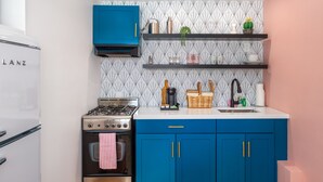 Une cuisine de taille réduite, équipée d’une cuisinière à gaz, d’un four et d’un meuble bleu.