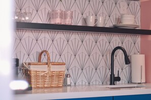 Een keuken met een geometrisch patroon op de achterwand, een zwarte kraan en een mand op het aanrecht.