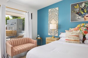 Un dormitorio con una cama, una mesita de noche, una lámpara, una silla y un cuadro de una mariposa en la pared.