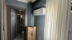 Un couloir avec une armoire en bois, un appareil de climatisation blanc et une porte donnant sur une autre pièce.