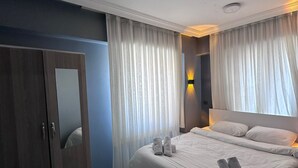 Une chambre d’hôtel équipée d’un lit, d’une armoire, d’un miroir et d’un luminaire fixé au mur.