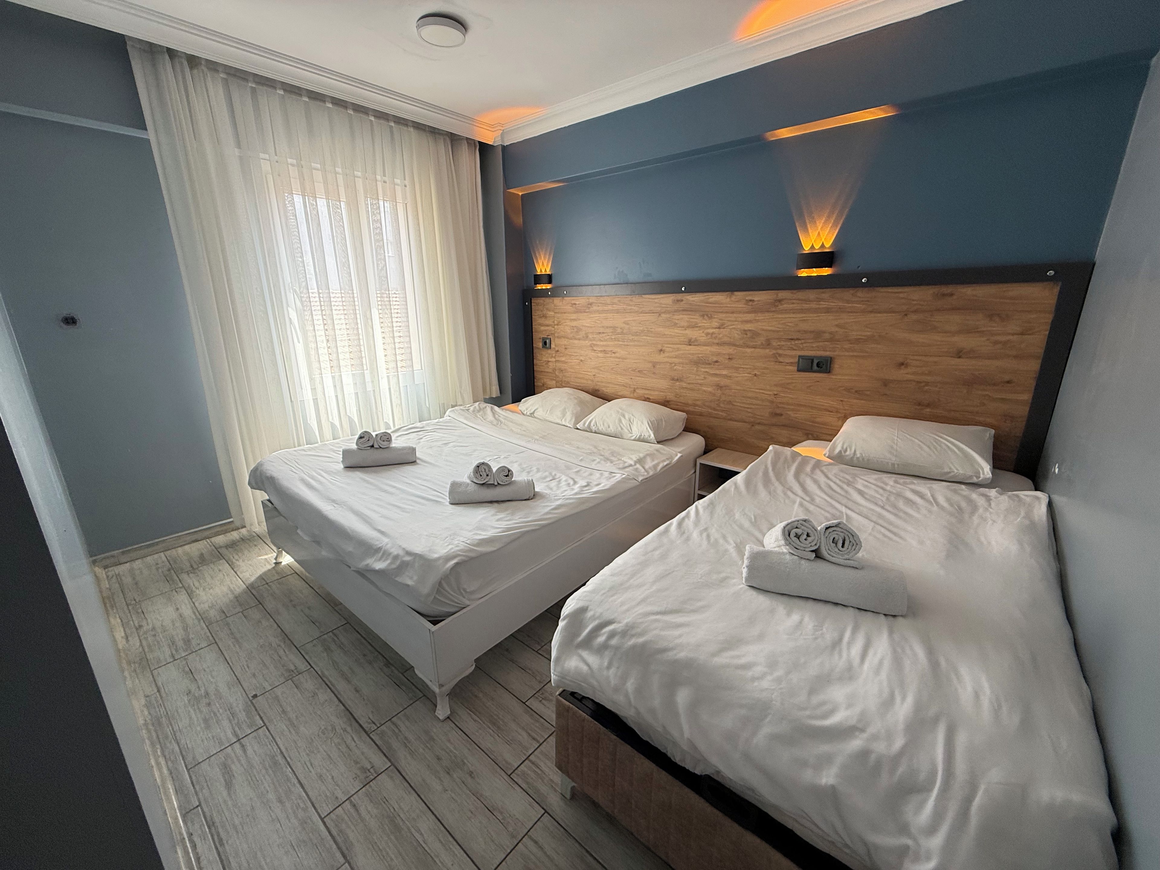 Une chambre d’hôtel avec deux lits, une tête de lit en bois et une table de chevet.