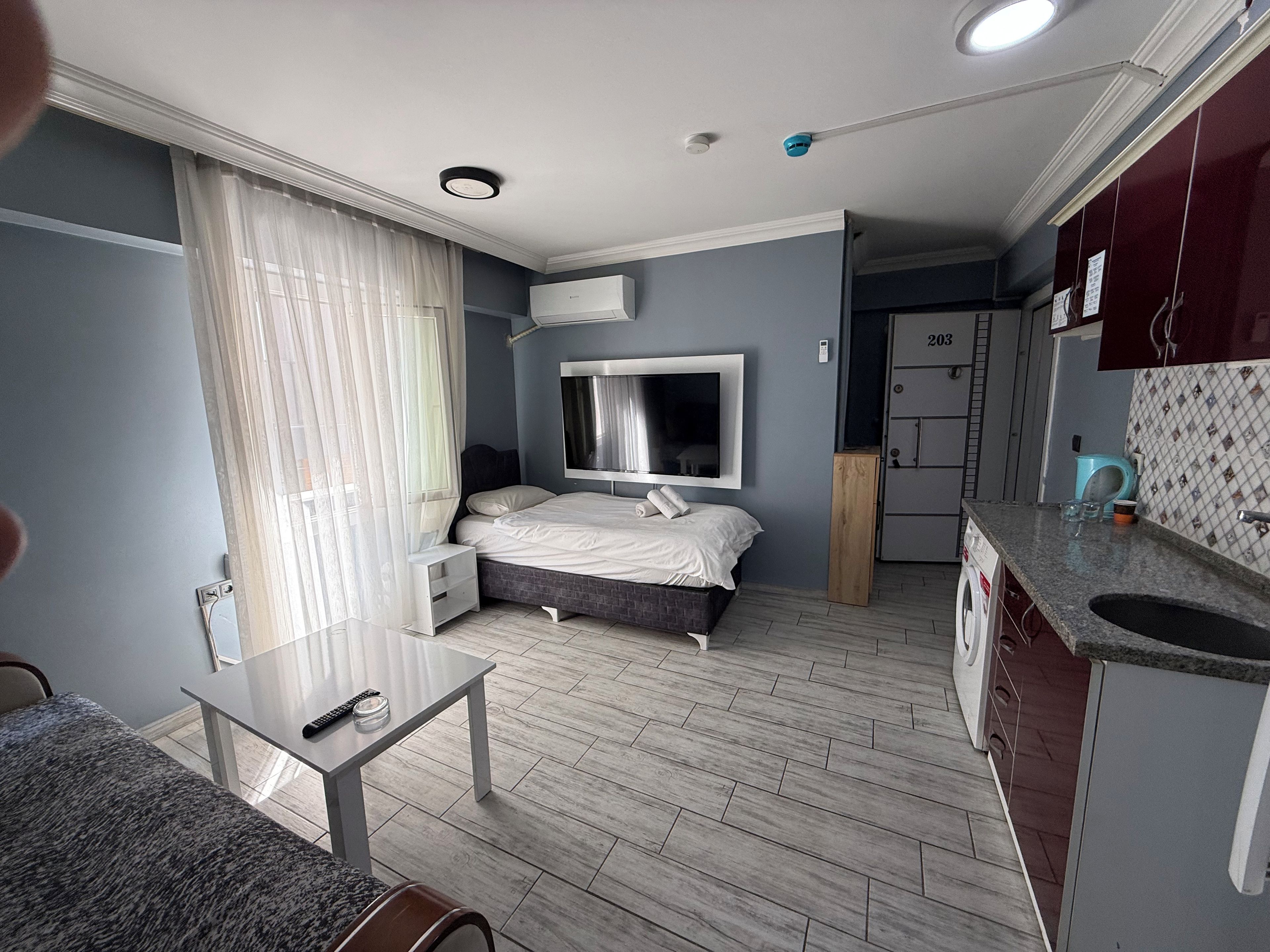 A modern bedroom with a bed, bedside tables, a TV, and a window with curtains.