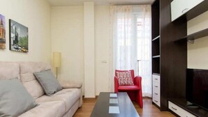 Ein Wohnzimmer mit einer Couch, einem roten Sessel, einem Couchtisch und einem Fernseher.