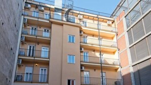 Ein mehrgeschossiges Wohnhaus mit Balkonen und Klimaanlagen unter blauem Himmel.