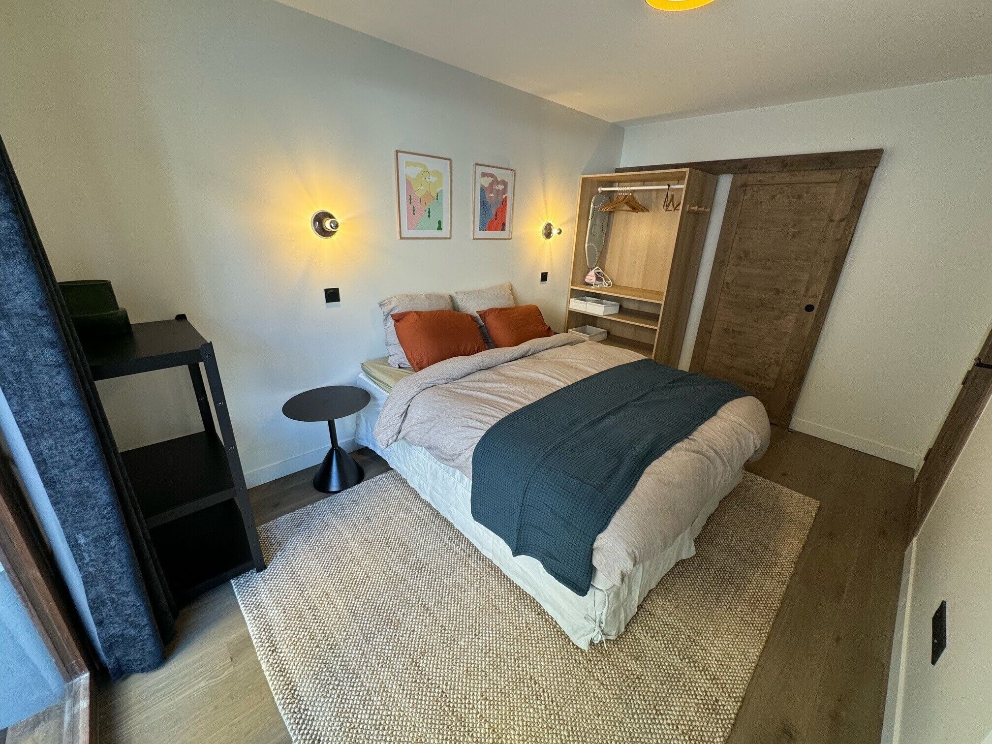 A bedroom with a bed, bedside tables, a wardrobe, and wall-mounted lights.