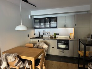 Enjoy meals in this kitchen with sleek cabinetry and stainless steel appliances, accompanied by a dining table and chairs.