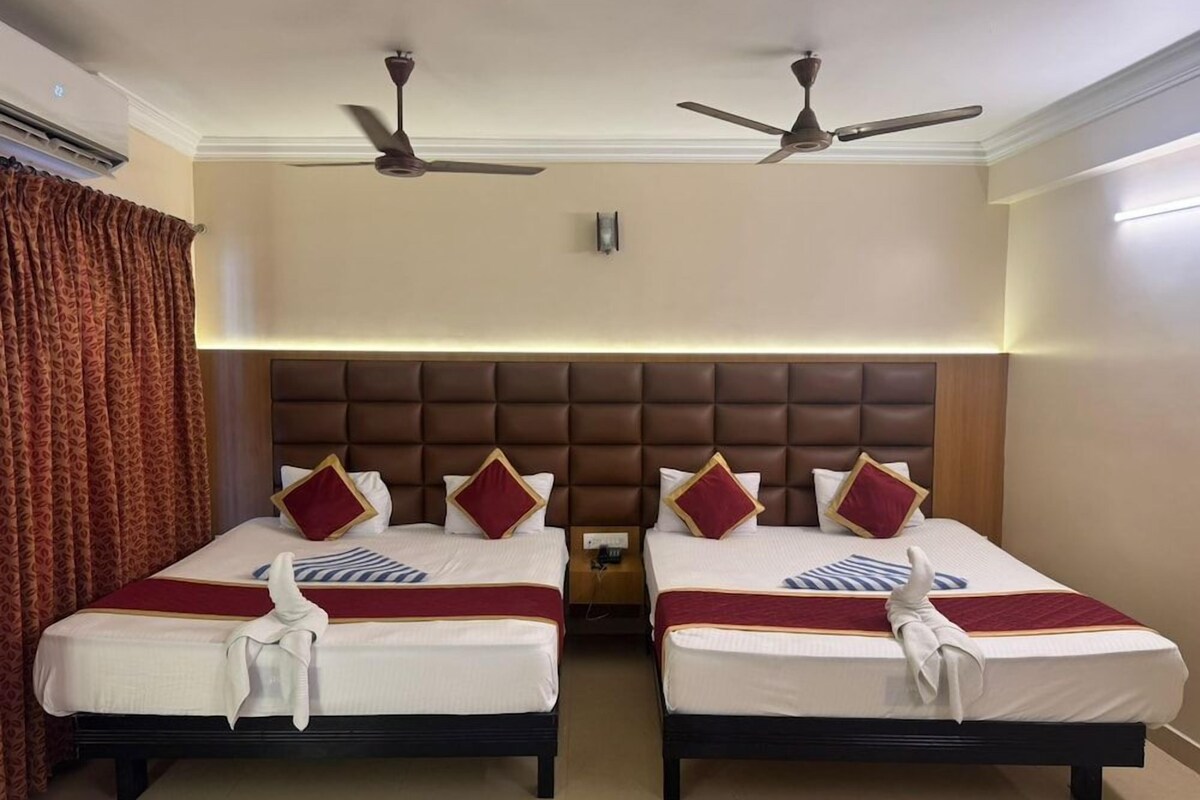 Habitación de hotel con dos camas, cabecero marrón, ventiladores de techo y una cortina roja.
