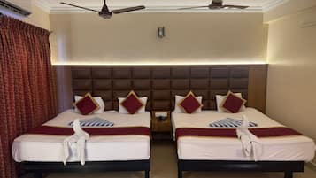 A hotel room with two beds, each with a headboard, a ceiling fan, and a nightstand.