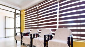 A waiting area with a row of covered chairs and tables, a striped wall, and a glass door entrance. - HOTEL SRIMANIYA (Nagercoil)
