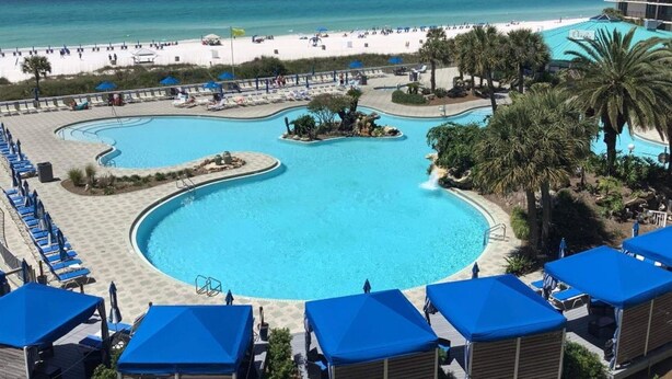 Un complexe hôtelier doté d’une grande piscine, d’une plage et de palmiers.