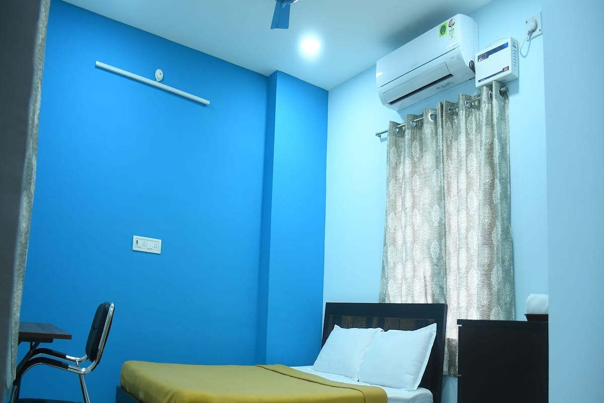 Ein Schlafzimmer mit Bett, Schreibtisch, Stuhl, Deckenventilator und Klimaanlage.