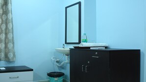 Een badkamer met een wastafel, spiegel en een zwart kastje.