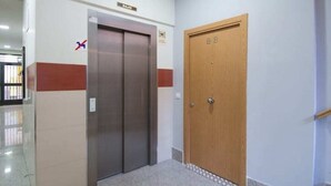 An elevator and a wooden door in a hallway with a tiled floor. - Madrid - Studio BB Sol/gran Via (Madrid)