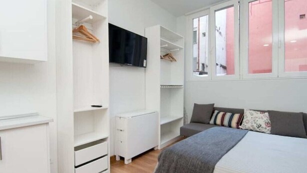 A bedroom with a bed, a wardrobe, a TV, and a window with a view. - Madrid - Studio BB Sol/gran Via (Madrid)
