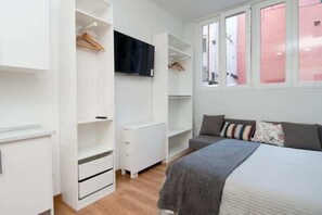A bedroom with a bed, a wardrobe, a TV, and a window with a view. - Madrid - Studio BB Sol/gran Via (Madrid)