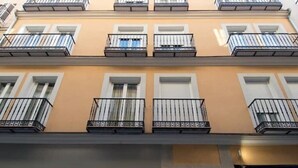 A multi-story building with balconies, a garage door, and a visible address number. - Madrid - Studio BB Sol/gran Via (Madrid)