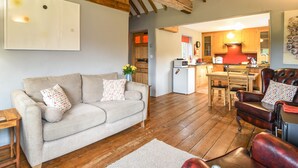 Ein gemütliches Wohnzimmer mit einer Couch, einem Sessel und einem Essbereich mit Tisch und Stühlen.