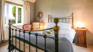 Ein Schlafzimmer mit Bett, Kommode, Stuhl, Fenster und Lampe.