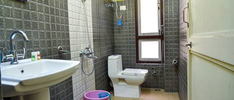 A compact bathroom with a sink, toilet, and shower.