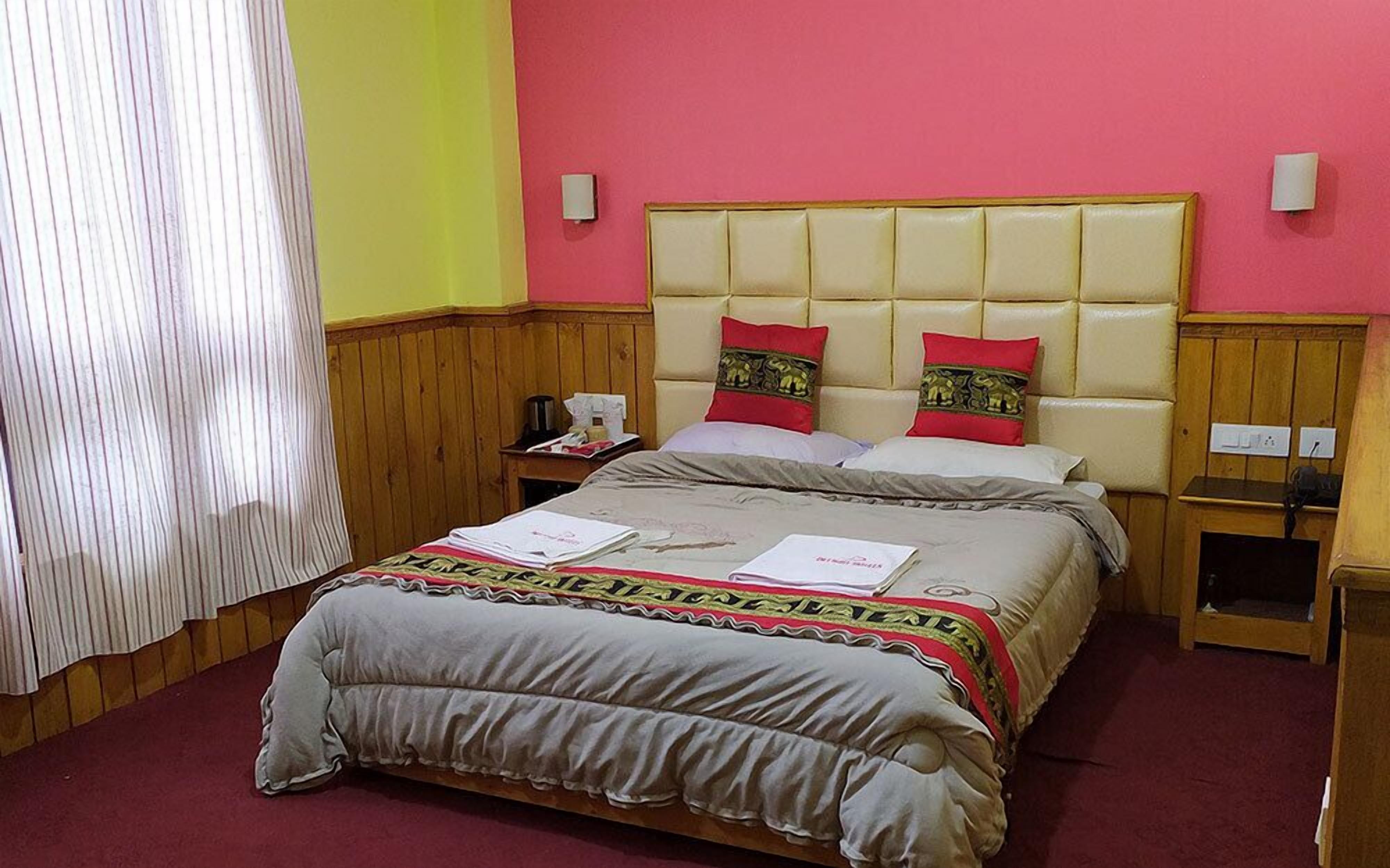 A hotel room with a bed, wooden headboard, two bedside tables, and a nightstand.