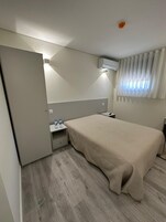 Ein Hotelzimmer mit Bett, Nachttisch und Klimaanlage.