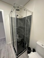 Ein modernes Badezimmer mit einer Duschkabine, Marmorfliesen, einer Toilette und einem Bidet.