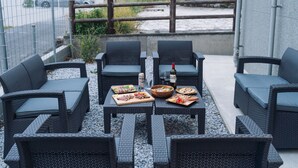 Un espacio para comer al aire libre con mobiliario de mimbre y una variedad de platos.