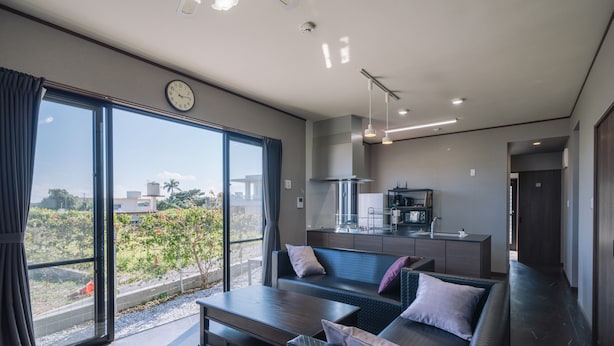 Una sala de estar moderna con un sofá, una mesa de centro y vistas al exterior a través de amplios ventanales.