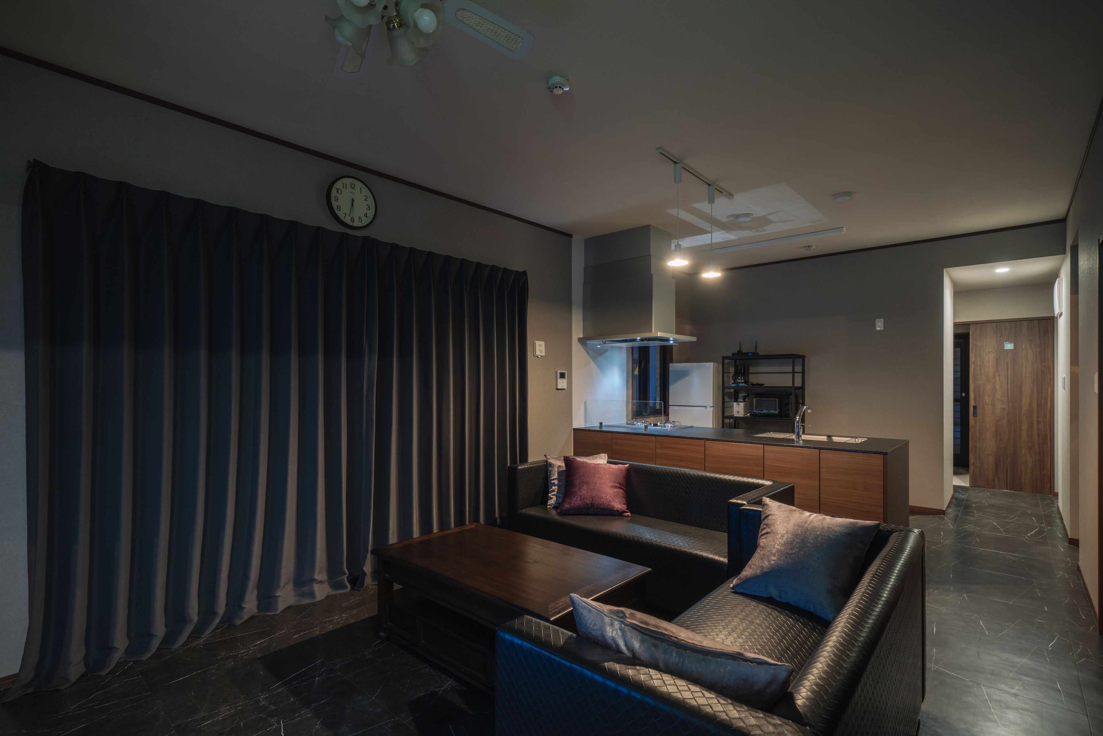 Una sala moderna con sofá, mesa de centro y una cocina al fondo.