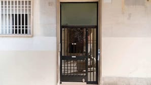 A building entrance with a metal gate and a window with bars. - Barcelona - Arte (Barcelona)