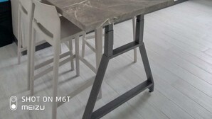 Una cuina moderna amb taulell de marbre, armaris blancs i una cafetera.