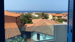 Zona residencial amb teulades de rajola terracota, cel blau clar i vista al mar.