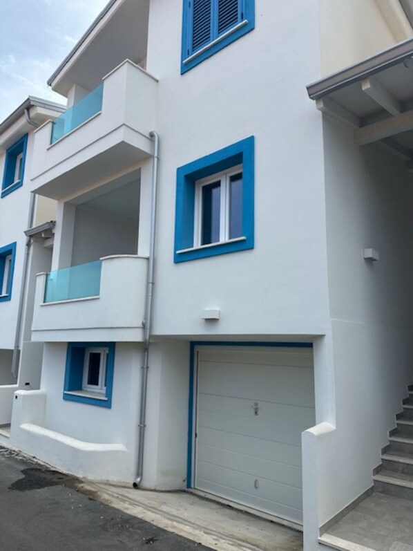 Un immeuble résidentiel à plusieurs étages, doté de balcons, d’un garage et d’un escalier.