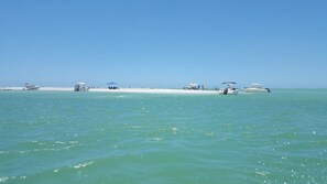 Een strand met boten, parasols en mensen.