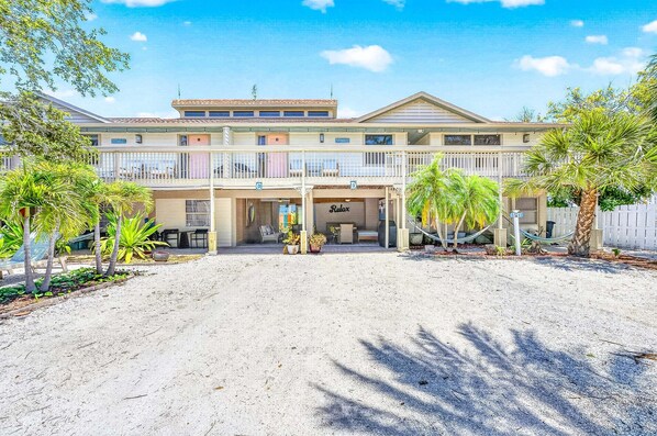 Un hotel con un área exterior cubierta, palmeras y un cartel que dice 'Relax'.