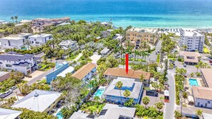 An aerial view of a coastal residential area with a prominent red flag, a swimming pool, and a beach in the background. - Gertrude's Siesta | 8-steps to Beach Path! 4-min Dining & Music! Hammocks, Snorkeling, Sunsets! (Siesta Key)