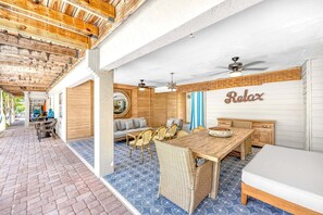 A covered outdoor area with a dining table, chairs, and a sofa.