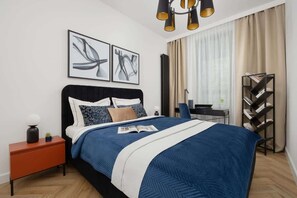 A modern bedroom with a large bed, a nightstand, a reading lamp, and abstract artwork on the wall. - Elegant Apartment with Balcony | Close to Metro, Place to Work (Warszawa)
