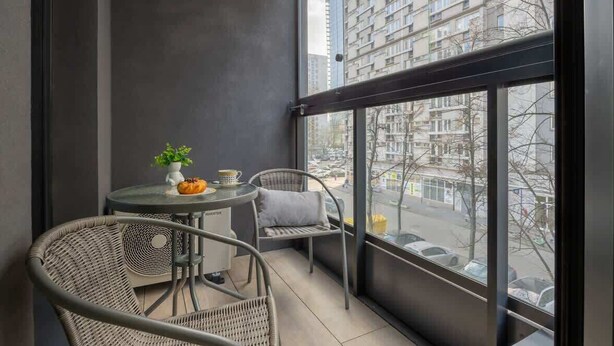 Un balcón con una mesa y sillas, una planta en maceta y vistas a la ciudad.